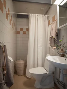 Modern minimalist bathroom with white ceramic tiles, a white toilet, a white sink, and a white shower curtain.