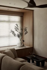 Modern living room with natural stone and wooden accents, featuring a cozy sofa and a peaceful corner plant.