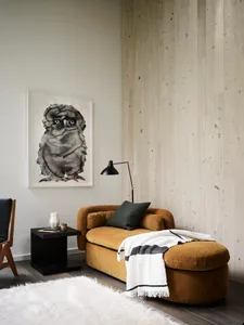 A modern living room with a comfortable mustard-colored sofa, a black floor lamp, a framed picture of an owl, a small black s
