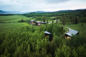 Aerial view of modern residential buildings surrounded by greenery and trees against a cloudy sky.