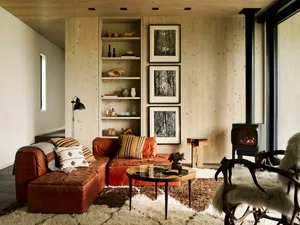 A cozy living room with a rustic sofa, bookshelf, and wood-paneled walls.