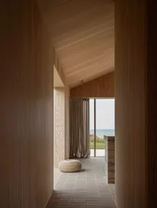 A minimalist beachfront hallway with wooden paneling and a view of the ocean.