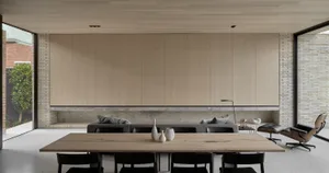 極簡客廳以磚牆與混凝土家具為特色，搭配大型木桌與黑色餐椅。