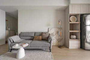 A minimalist living room with a gray couch adorned with cushions, a white coffee table, and a modern design aesthetic.