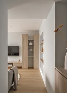 A minimalist living room with wooden shelves and a gray sofa.
