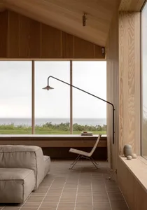 A minimalist living room with wooden window seat, views of the sea, and modern furniture.