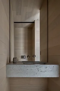 A modern bathroom with concrete walls and a mirror above a sink.