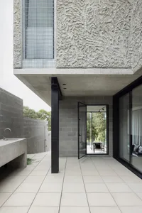 Modern exterior design featuring a textured concrete facade and large glass doors.