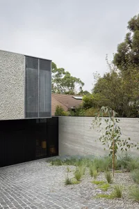 Modern exterior house extension made of concrete materials, featuring a grid-pattern design on the wall.