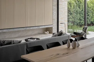 Modern living room featuring a concrete fireplace with a wood table and black chairs.