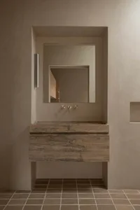 Modern minimalist bathroom with concrete walls and floor, featuring a floating vanity sink with a matching minimalist faucet 