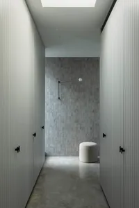 現代極簡浴室，鋪設混凝土瓷磚與地板，搭配單盞燈具與白色凳子。