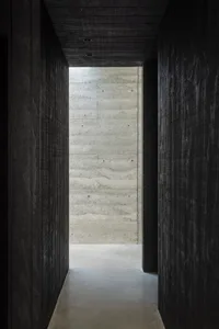 A minimalist interior with concrete walls and a hallway.