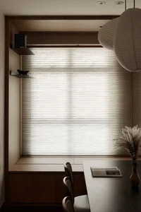 A minimalist interior space featuring a window seat with textured wood seating and fabric blinds.