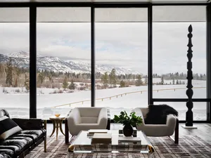 Modern residential interior with glass windows, concrete flooring, and upholstered furniture.