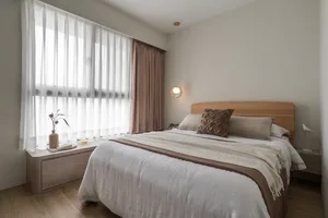 A minimalist bedroom with a light-colored bed, white and brown curtains, and a wooden headboard.