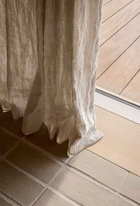 Lightweight textured linen curtains with a subtle striped pattern hanging in a natural wooden floor setting.