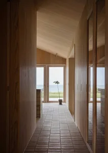 A wooden hallway in a marine-style residence with a door leading to an exterior view of the sea.