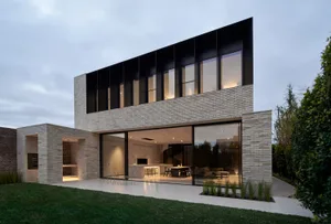 A modern house with a brick-clad exterior and large glass windows.