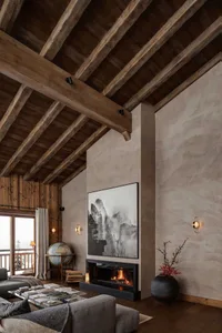 A modern living room featuring wooden beams, a fireplace, and a globe on a bookshelf.
