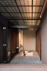 A minimalist living room with concrete flooring and wooden accents, featuring a single wooden floor lamp.
