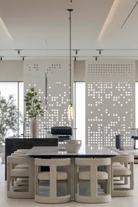 Minimalist dining room with concrete floor, fabric-covered chairs, and modern lighting.