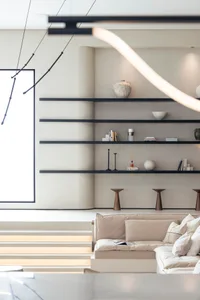 A minimalist living room with concrete walls, floating shelves, and a wooden sofa and coffee table.