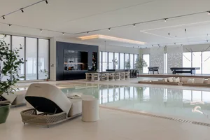 Modern minimalist living space featuring a swimming pool and concrete and glass architectural elements.