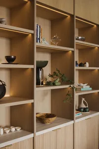 Modern living room with wooden shelves displaying books, vases, and decorative objects.