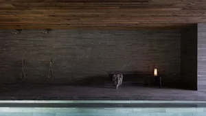 A serene spa poolside relaxation area with granite and stone walls, wood flooring, and a lantern.