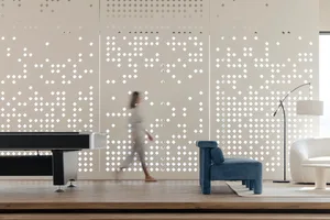 A modern minimalist living room features a wooden floor, a blue armchair, and a white sofa with a floor lamp.