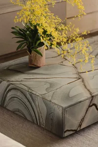Modern coffee table with a marble top featuring intricate vein patterns, placed on a soft, plush carpet.
