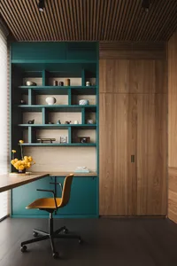 A modern home office featuring a teal storage unit and wooden paneling.