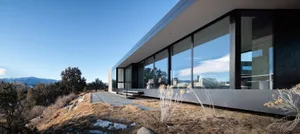 Modern house featuring large glass walls and concrete exterior.