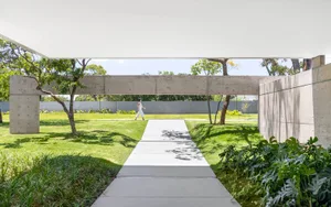A modern concrete pathway amidst lush greenery, leading to a serene outdoor space.