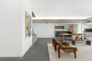 A modern living room with concrete walls, minimalist furniture, and large windows.