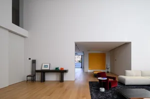 A modern Scandinavian living room with minimalist design elements, featuring a large wall, wooden flooring, and a mix of furn