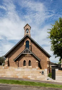 A brick church with a bell tower and large windows.