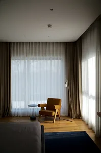 A minimalist bedroom with a wooden bed, fabric rug, and metal lamp.