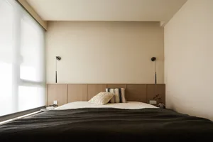 A minimalist bedroom with a wooden panel bed, white bedding, and simple wall sconces.