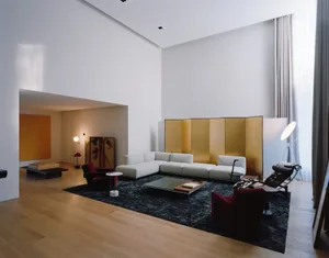 A minimalist living room with a white sofa, red armchairs, and wooden floor.
