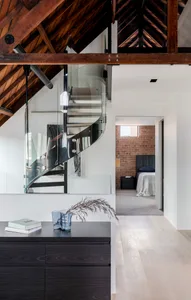 A modern bedroom featuring glass stairs and a wooden floor.
