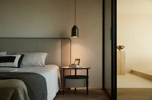 Modern minimalist bedroom with a sleek bed, side table, and minimalist decor.