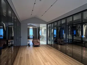 Modern clothing closet with glass walls showcasing a variety of garments for fashion design.