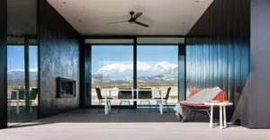 Modern living room featuring black-framed windows overlooking snowy mountains.