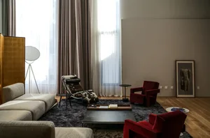 A modern living room featuring a mix of materials and textures, including a textured rug, wooden floor, and contemporary furn