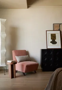 A modern living room with a textured fabric armchair, wooden side table, and abstract artwork on the wall.