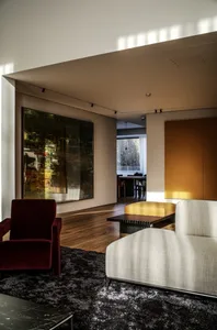 Modern living room featuring wood floors, concrete walls, and minimalistic furniture.