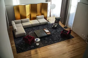 Modern living room featuring a comfortable sofa, armchairs, a coffee table, and a decorative copper screen.