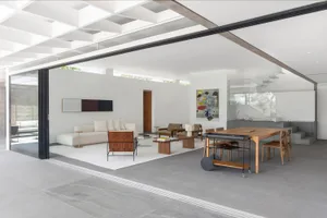 A modern minimalist living room featuring concrete, glass, and wooden elements. Includes a white sofa, wooden coffee table, a